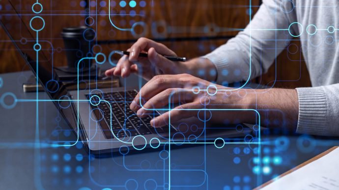 Hands typing the keyboard to create innovative software to change the world and provide a completely new service. Close up shot. Hologram tech graphs. Concept of Dev team.