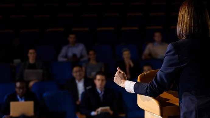 Rear view of female business executive giving a speech at conference center